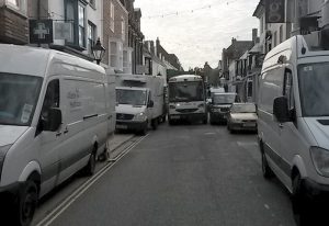 Caught in the middle: a refuse lorry is unable to go forward in the High Street, its way blocked by white vans and a 4x4 which sticks out of a parking zone